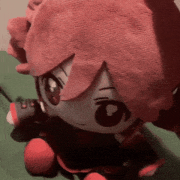 a stuffed animal with red hair is sitting on a bed with a microphone .
