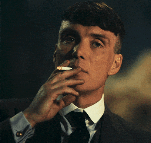 a man wearing a suit and tie is smoking a cigarette