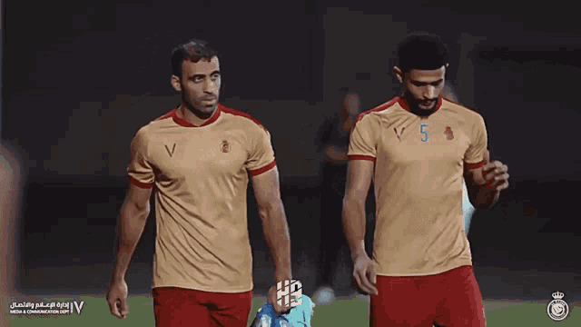 two soccer players on a field with the letter v on the front of their shirts