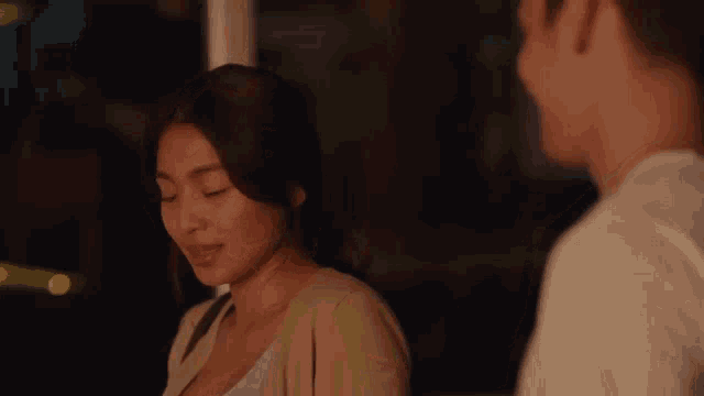 a man and a woman are standing next to each other and looking at each other with their eyes closed .