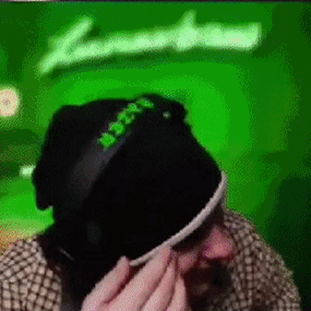 a man wearing a black hat with the word xbox on it is covering his eyes