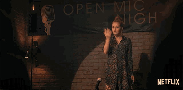 a woman dances in front of an open mic night sign