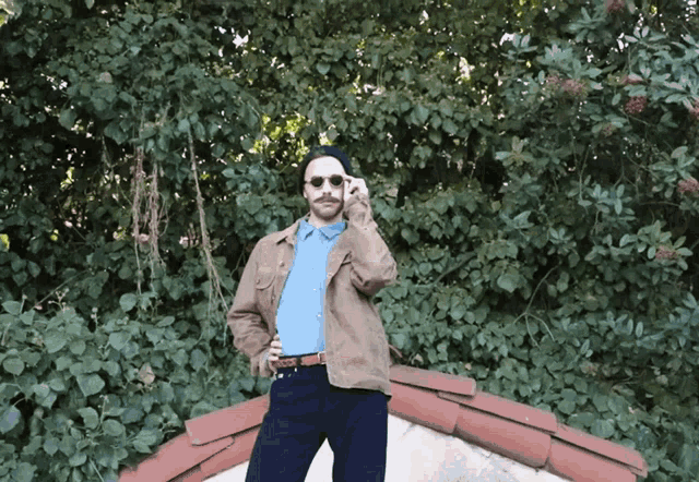 a man wearing sunglasses and a blue shirt is standing on a roof