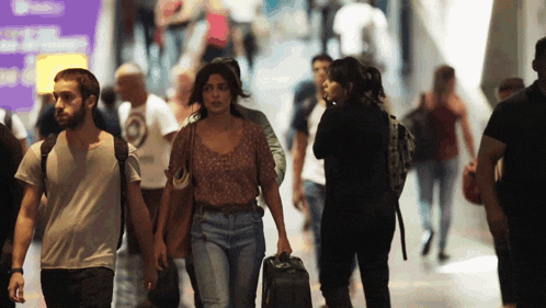 a woman carrying a suitcase walks in a crowded area