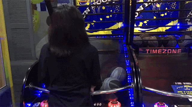 a woman is playing a game called timezone in an arcade