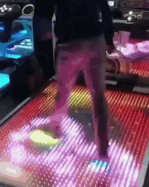 a person is walking on a glowing dance floor in a dark room .