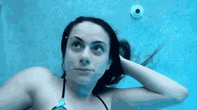 a woman in a bikini is swimming under water