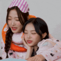two girls are laying next to each other with their eyes closed and one is wearing a party hat .