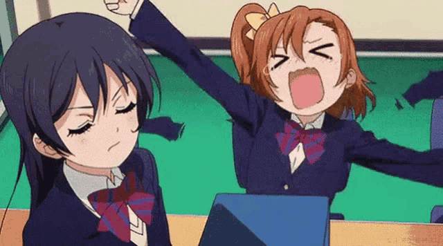two anime girls are sitting at a table with their arms in the air .