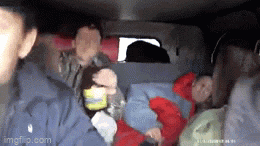 a man is holding a bottle of beer in the back of a police car .