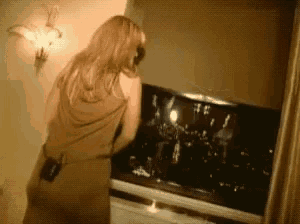 a woman in a brown dress is standing in front of a tv screen