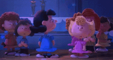 a group of peanuts characters are standing around a table with hearts on them .