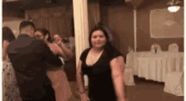 a group of people are dancing in a room at a wedding reception .