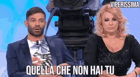 a man and a woman are sitting in front of a camera with the words quella che non hai tu written on the bottom