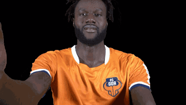 a man with a beard wears an orange shirt that says fc gor