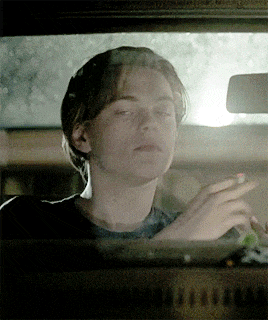 a young man is smoking a cigarette while driving a car