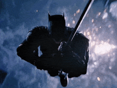 a man in a batman suit is flying through the air with a sword