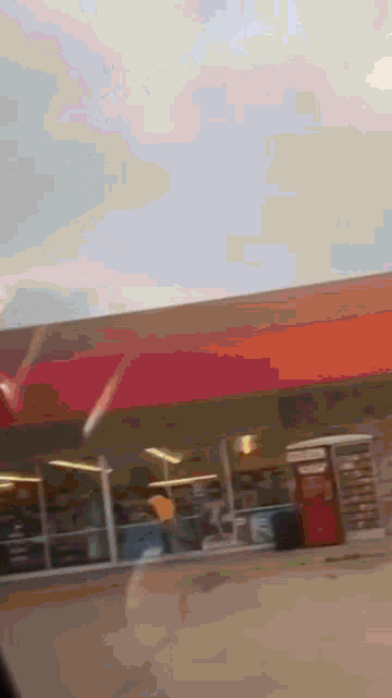 a gas station with a red awning and a red vending machine in front of it