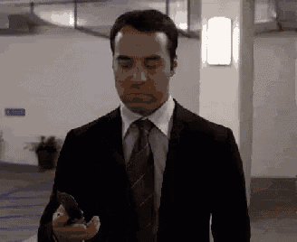 a man in a suit and tie is looking at his cell phone .