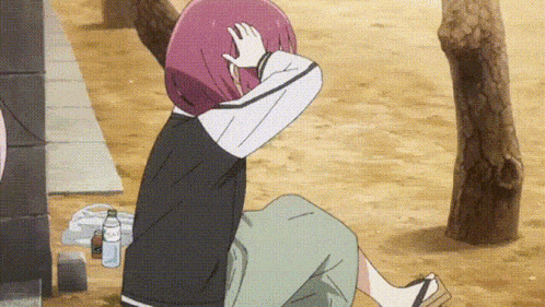 a girl with purple hair is sitting on the ground covering her face with her hands .