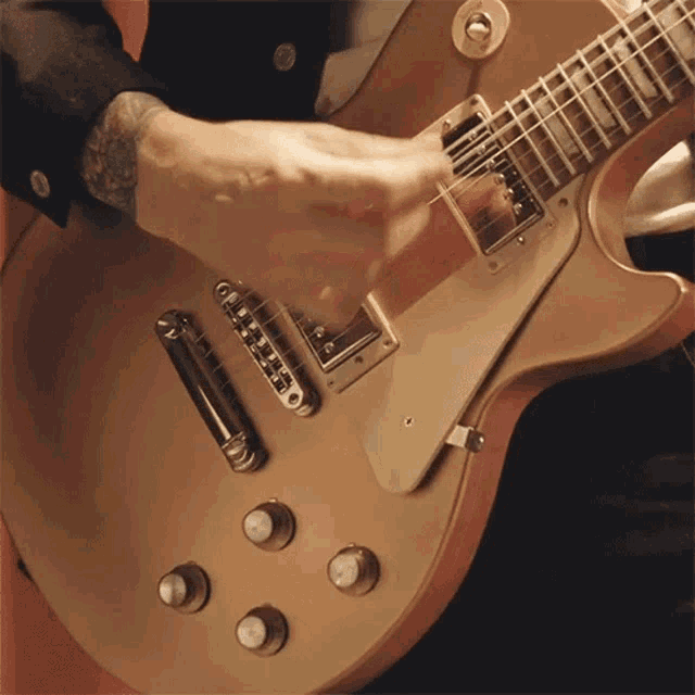 a man is playing a guitar with a tattoo on his arm