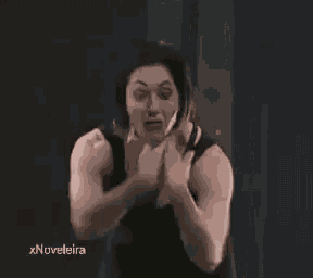 a woman in a black tank top is flexing her muscles .