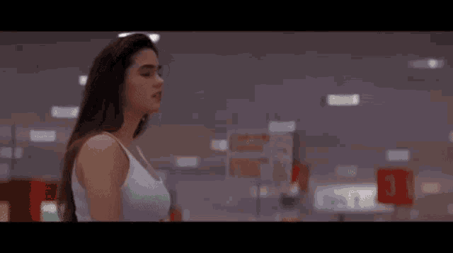 a woman in a white tank top is standing in a store .