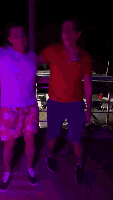 a man in a red shirt is dancing with another man in a white shirt