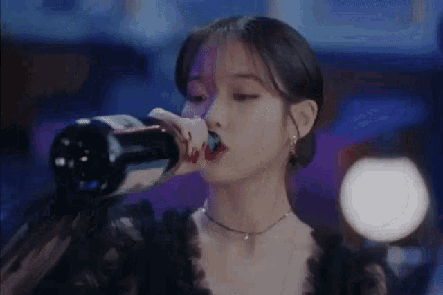a woman is drinking from a bottle of wine at a party .