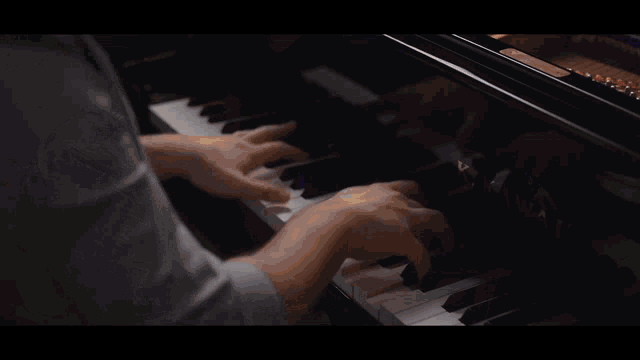 a man is playing a piano and singing into a microphone