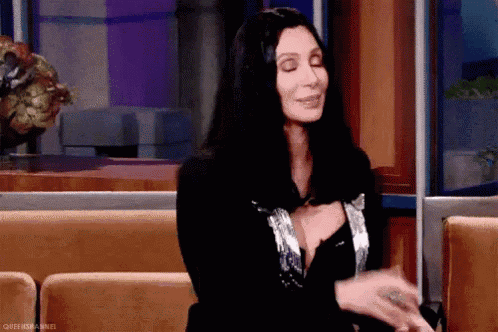 a woman in a black dress is sitting on a couch with her eyes closed .