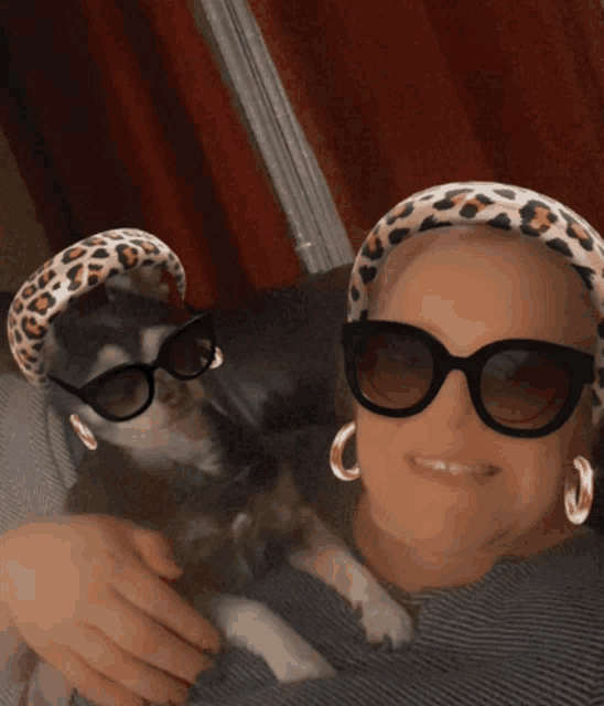 a woman wearing sunglasses holds a small dog
