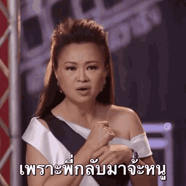 a woman in a black and white dress holds her hands to her chest in front of a sign that says ' thailand ' on it