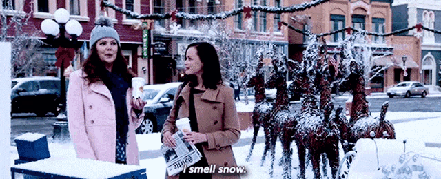 two women are standing in front of a statue of a reindeer .