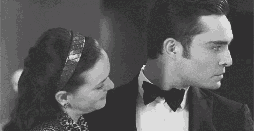 a man in a tuxedo and a woman in a headband are standing next to each other .