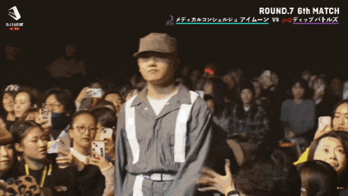 a man stands in front of a crowd with the word rei on the bottom right