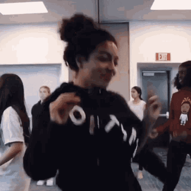 a group of people are dancing in a room with a red exit sign in the background .