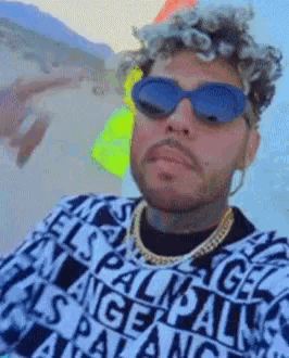 a man wearing sunglasses and a sweater that says palm angels on it