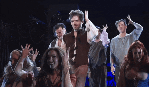 a group of people on a stage with their hands up