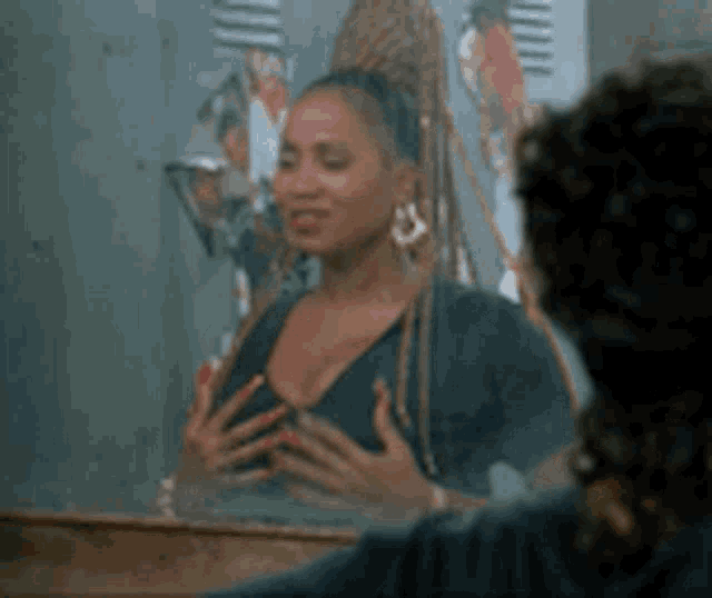 a woman is looking at her breasts in a mirror in a locker room .