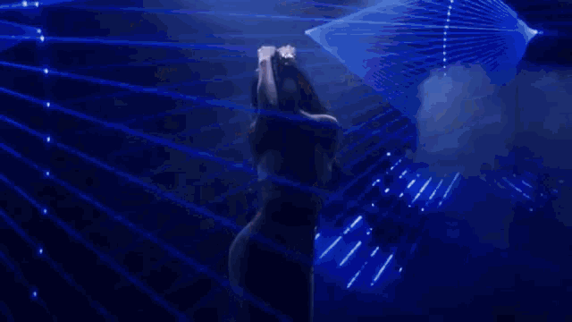 a woman in a white tank top and black necklace is dancing on a stage .