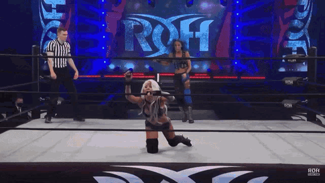 two women are wrestling in a ring with a large screen behind them that says roh on it