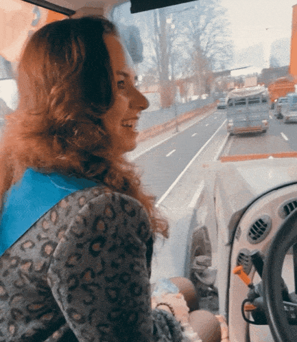 a woman in a leopard print jacket looks out the window of a vehicle