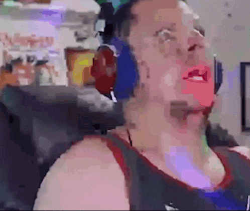 a man wearing headphones and a tank top is standing in front of a computer .