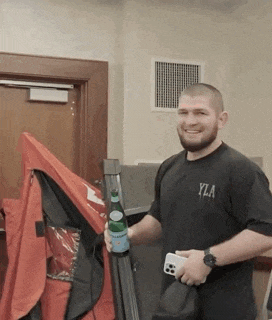 a man wearing a black shirt that says yza is holding a bottle of water