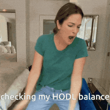 a woman in a blue shirt is checking her hodl balance on her phone