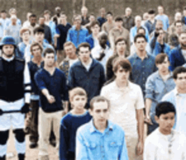 a large group of people are standing in a line including a man in a helmet