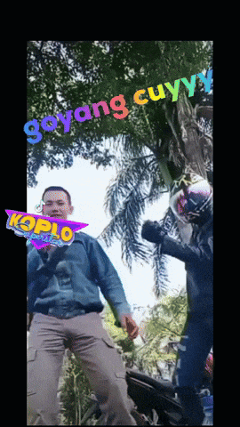 a man in a blue shirt stands next to a man in a pink helmet with the words goyang cuyyy written on it