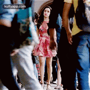 a woman in a pink dress is walking through a crowd .