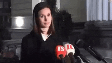a woman is standing in front of a row of microphones and talking into them .